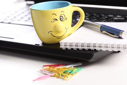 Lächelnde Kaffeetasse in Gelb auf dem Laptop
