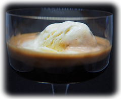 Halbschalen Glas mit einer Kugel Vanille-Eis. Diese ist übergossen mit einem doppelten Espresso. Serviert als Eiskaffee.