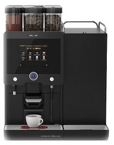 Kaffeevollautomat Coffee & Soul in Schwarz mit drei Produktbehältern für zwei Kaffeesorten, einmal Schocko und Touchdisplay. Unter dem Auslauf steht eine Weisse noch leere Kaffeetasse.